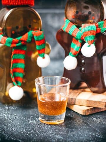 Easy homemade gingerbread simple syrup for coffees and cocktails in a small glass, placed next to two gingerbread man.