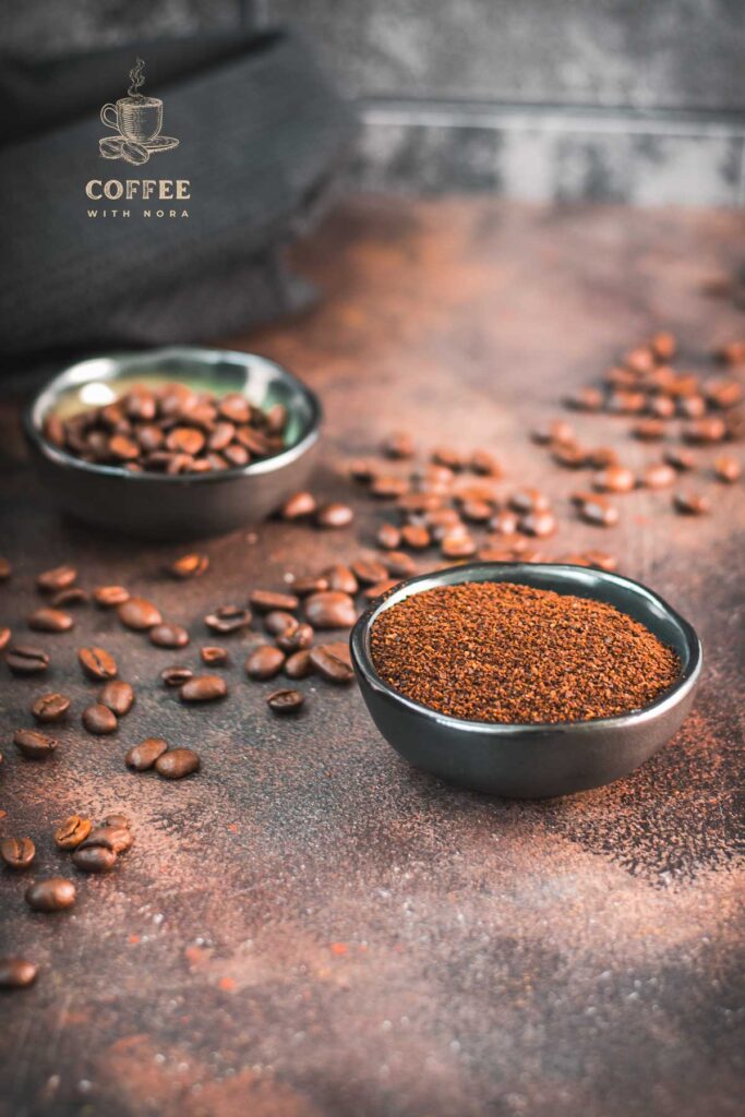 Two bowls, one with ground coffee one with coffee beans on brown ground.