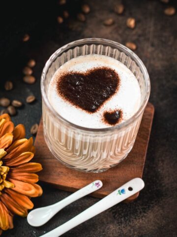 Gorgeous Cortado coffee, served in glass mug and dusted with cocoa powder.