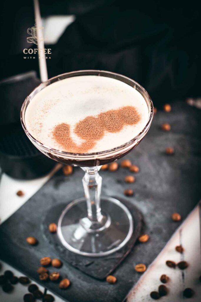 Cocktail glass, filled with a decadent Nespresso martini. Placed on a black slate plate, next to coffee beans.