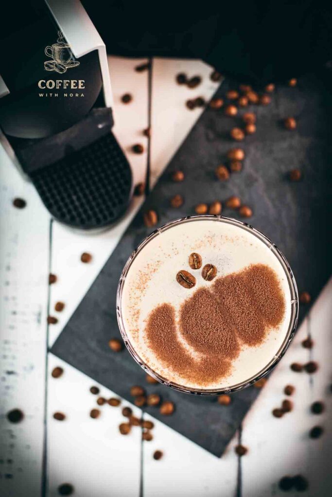 Cocktail glass, filled with a decadent Nespresso martini. Placed on a black slate plate, next to coffee beans.