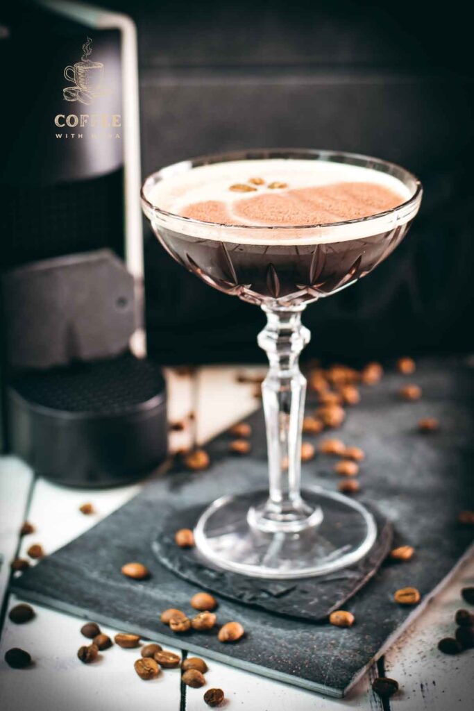 Cocktail glass, filled with a decadent Nespresso martini. Placed on a black slate plate, next to coffee beans.