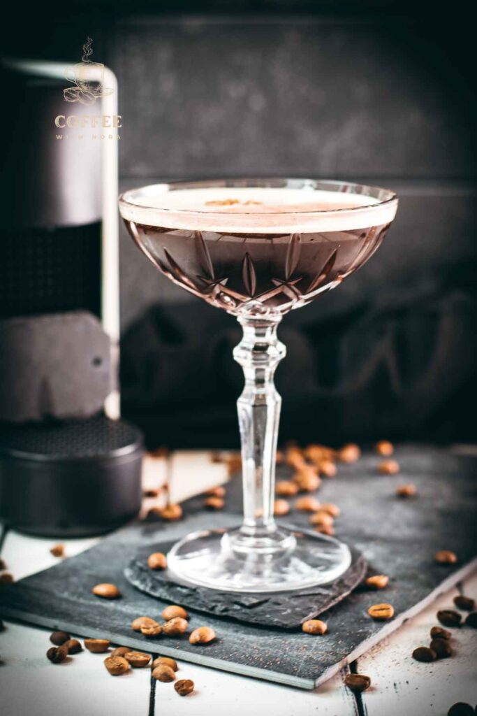 Cocktail glass, filled with a decadent Nespresso martini. Placed on a black slate plate, next to coffee beans.