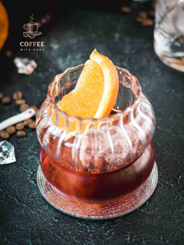 Gorgeous rocks glass, filled with a delicious cold brew negroni, garnished with an orange slice, and placed on a mirrored coaster.