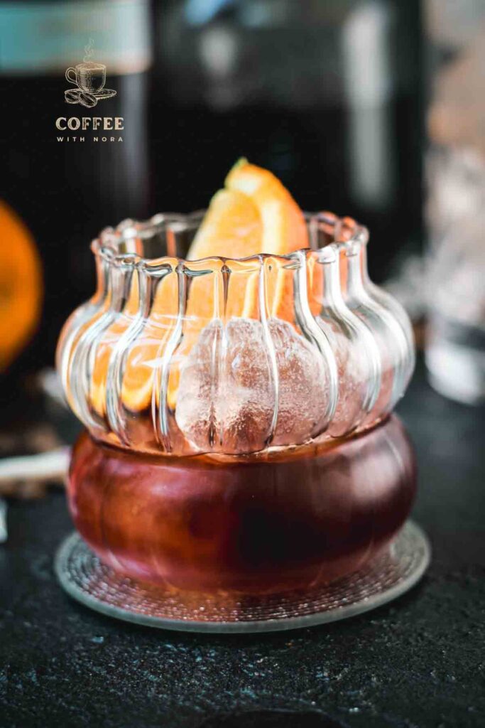 Gorgeous rocks glass, filled with a delicious cold brew negroni, garnished with an orange slice, and placed on a mirrored coaster.