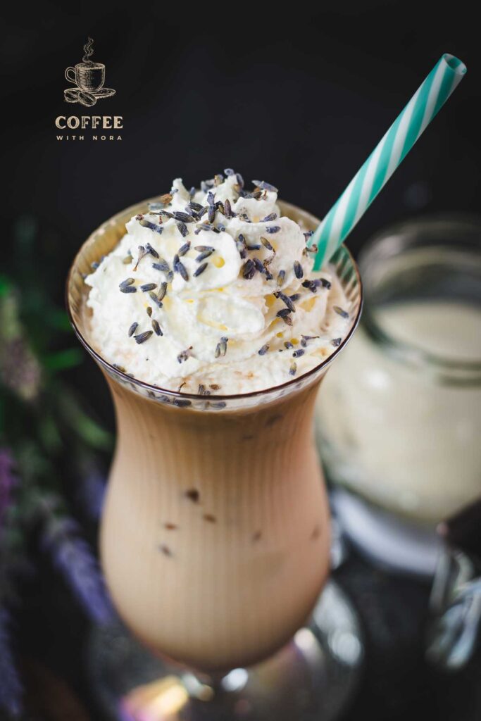 Gorgeous Hurricane glass, filled with crushed lavender iced latte, topped with whipped cream and sprinkled with lavender buds. Served with a turquoise white striped drinking straw.