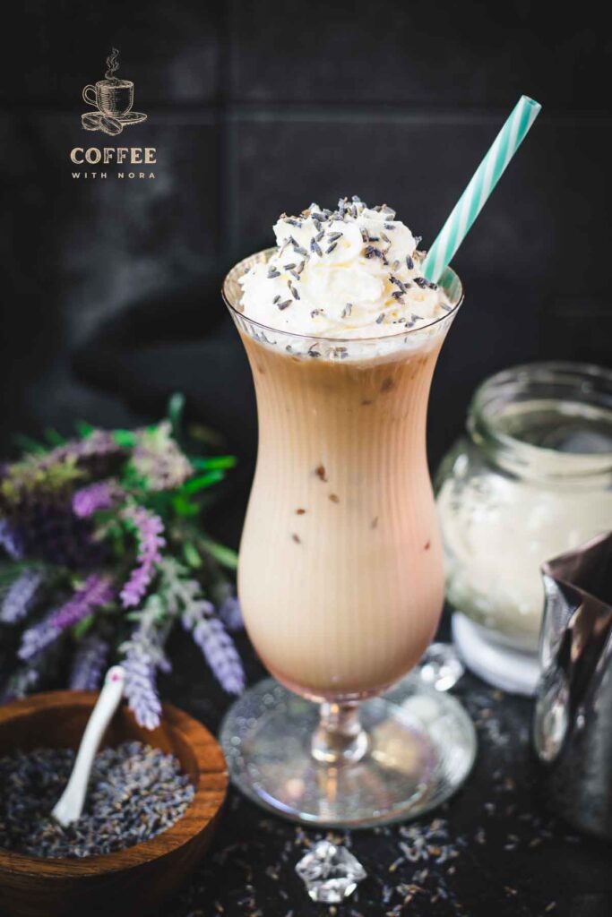 Gorgeous Hurricane glass, filled with crushed lavender iced latte, topped with whipped cream and sprinkled with lavender buds. Served with a turquoise white striped drinking straw.